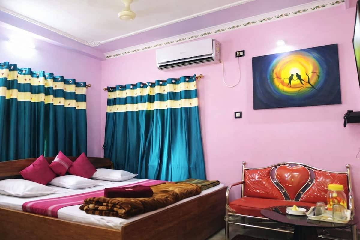 A bedroom with a bed, a chair, an air conditioner, and a painting on the wall.