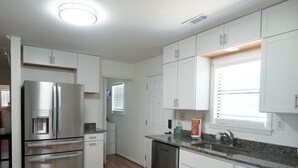A modern kitchen with white cabinets, stainless steel appliances, and a granite countertop.