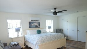 A bedroom with a bed, a nightstand, a chair, and a ceiling fan.