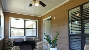 A dining area with wicker chairs, a glass table, and a ceiling fan.