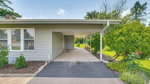 A house with a covered porch, a well-maintained lawn, and a small garden with various plants. - Near Dtwn Harrisburg: Stylish Home w/ Patio & Yard (Camp Hill)