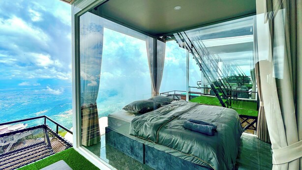 A bedroom with a large window, a bed, and a view of the landscape.