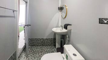 A small bathroom with a toilet, sink, and a mirror.