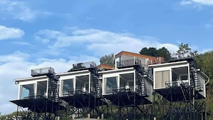 A series of elevated structures with external staircases, large windows, and a clear sky.