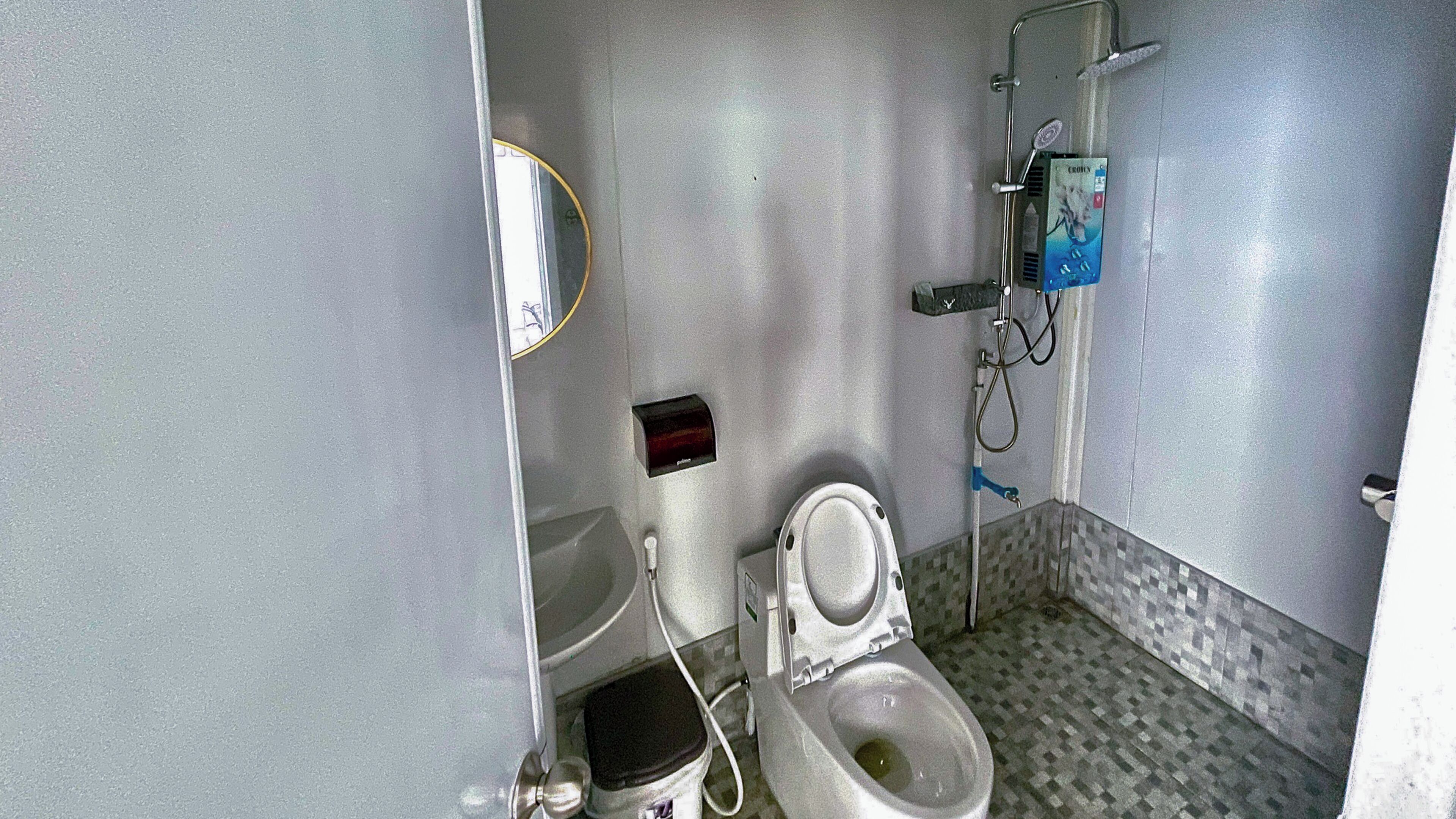 A bathroom with a toilet, a sink, a mirror, and a shower.