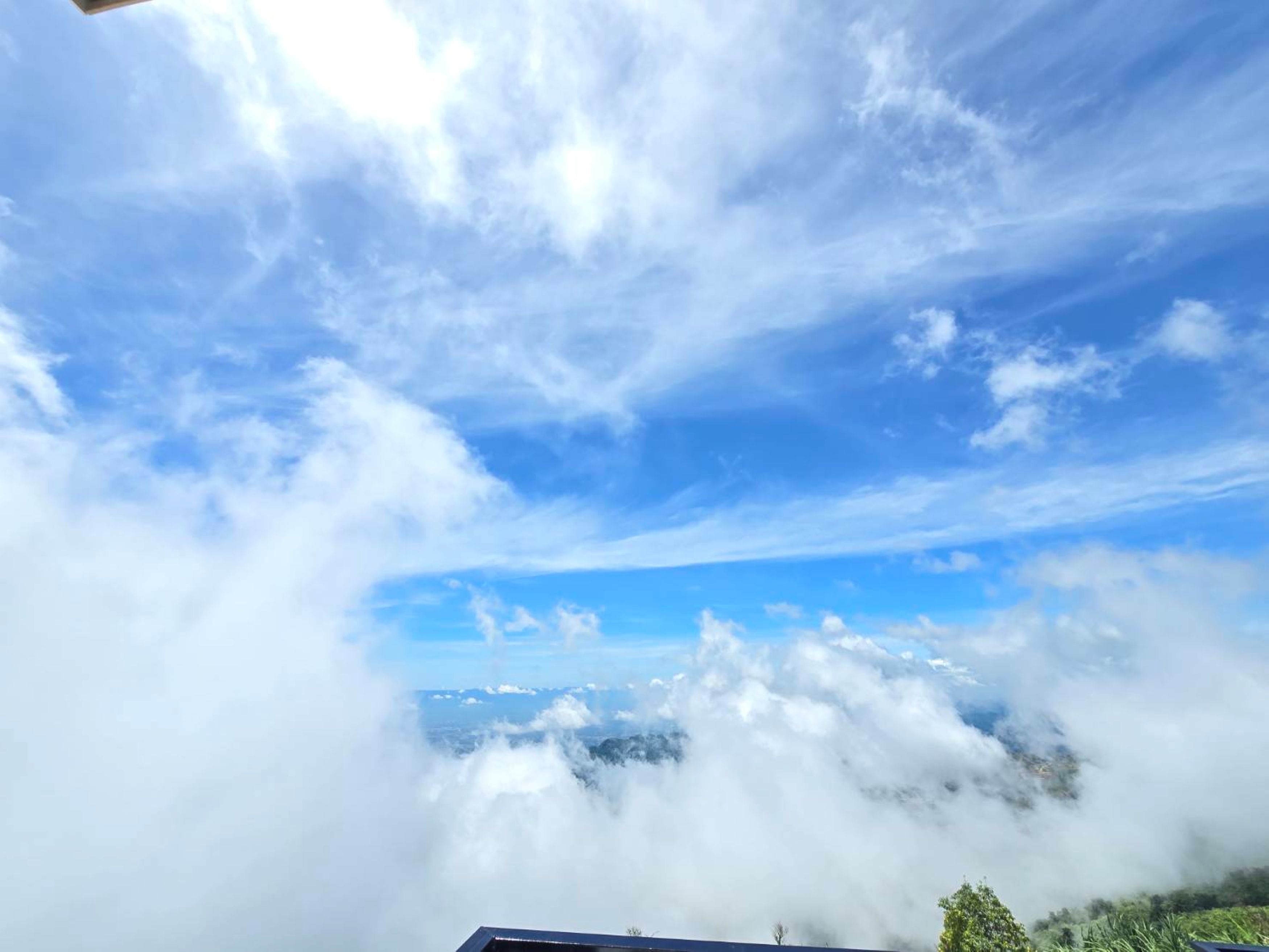 Une vue sur une chaîne de montagnes, en partie masquée par des nuages, avec un ciel dégagé au-dessus.