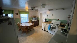 Une cuisine compacte comprenant une table à manger, un four à micro-ondes, une cuisinière et un réfrigérateur.