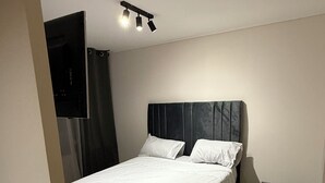 Une chambre à coucher avec un grand lit, une tête de lit, une table de chevet et un petit banc.