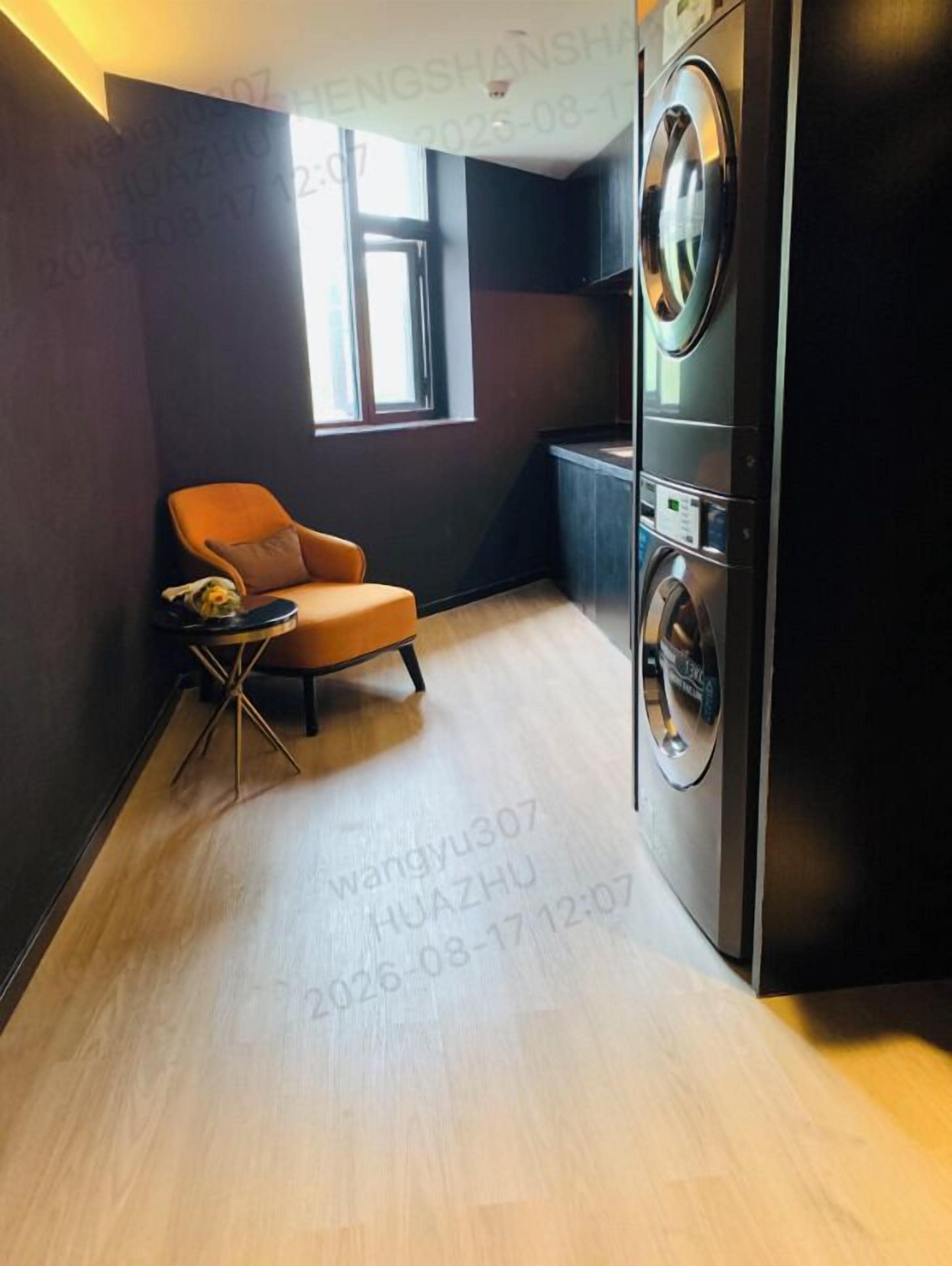 A compact room with a washing machine, a chair, and a small table.
