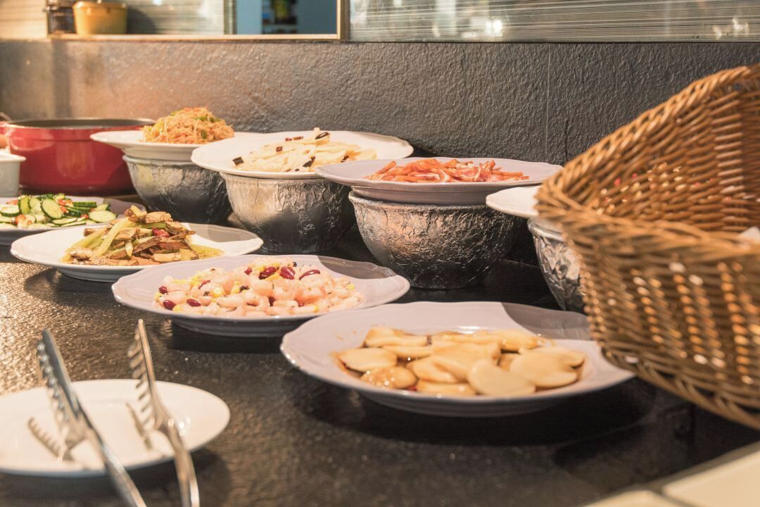 A buffet table with various dishes and a wicker basket.