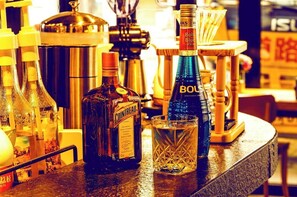 Una barra con botellas de licor, una máquina de café y un vaso.