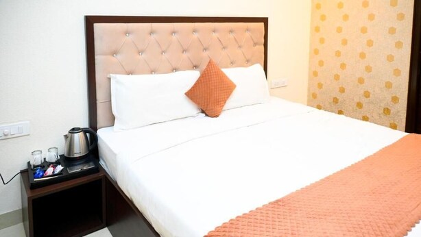 A hotel room with a bed, a nightstand with a coffee maker, and a patterned curtain. - HOTEL INFRAVIEW (Dera Bassi)