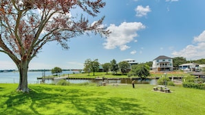 A lakeside property with a large tree, grassy areas, and a dock. - Yard & Dock: Waterfront Group Getaway in Biloxi (Biloxi)