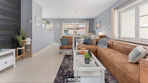 Una sala de estar moderna con sofá, mesa de centro y mueble para televisión.