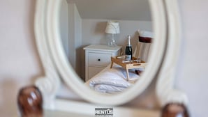 Un dormitorio con una cama, una mesita de noche con lámpara y una botella de champán.