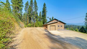 Ein zweistöckiges Gebäude mit Garage, umgeben von einer Schotterstraße und dichtem Wald.