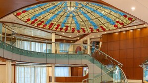 Un amplio vestíbulo con un techo grande y ricamente decorado y un piso circular de mármol.