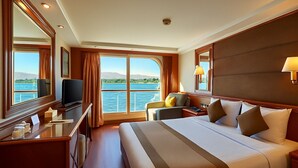 Habitación de hotel con una cama grande, un escritorio, una silla, un televisor y una ventana con vista al agua.