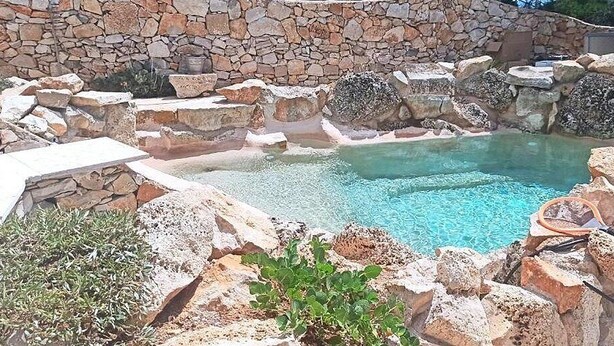 A swimming pool surrounded by rocks and stone walls.