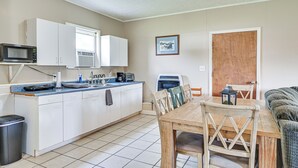 A compact kitchen with white cabinets, a microwave, and a dining area with a wooden table and chairs.