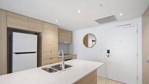 Una cocina moderna con encimera blanca, pileta de acero inoxidable y muebles de madera.