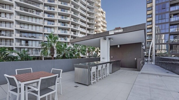 Un patio al aire libre con mesa y sillas, una zona de bar y vistas a un edificio de gran altura.