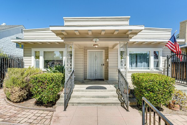 A two-story house with a front porch, a garage, and a driveway. - Miracle Mile Stay: Classic Stockton Home w/ Yard! (Stockton)