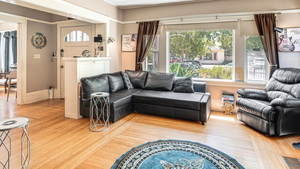 Ein Wohnzimmer mit einer Eckcouch, einem Ledersessel, einem runden Couchtisch und einem gemusterten Teppich.