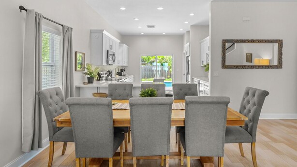 A modern dining area with a wooden table and grey upholstered chairs.