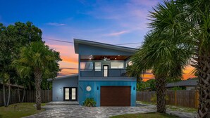 A modern two-story house with a balcony, a garage, and a paved driveway.