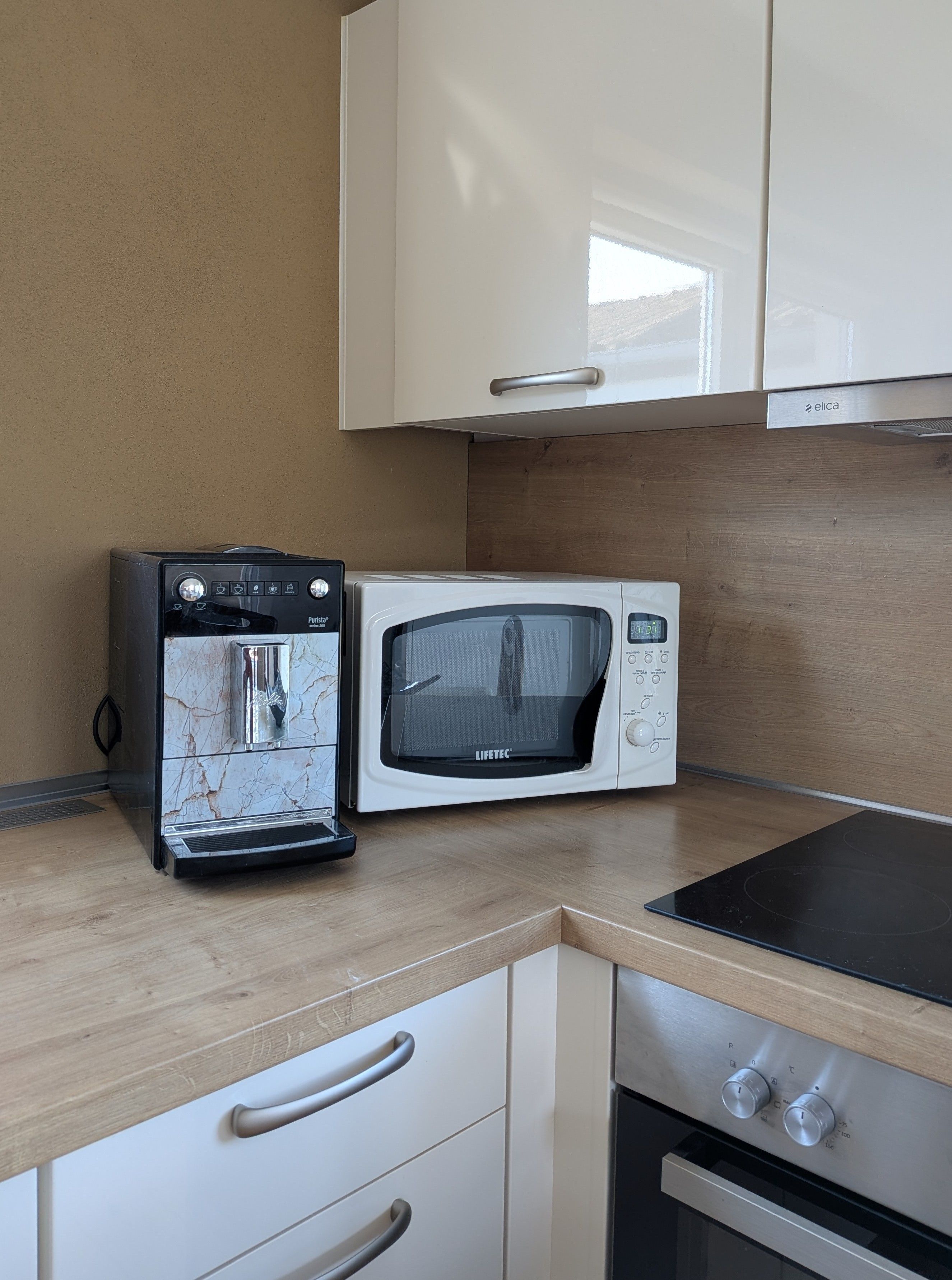 Een kitchenette met een koffiezetapparaat, magnetron en oven.