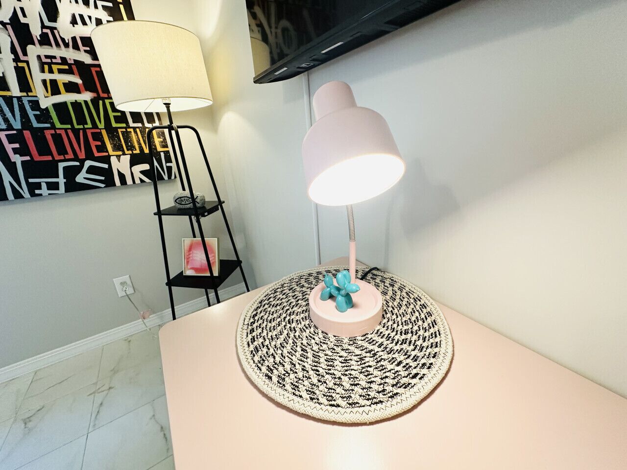 A modern room with a round table, a lamp, and a wall art piece.