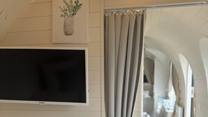 Een moderne slaapkamer met een bed, een wandtv en uitzicht op een gang.