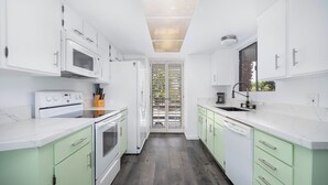 Una cocina moderna con armarios blancos, horno integrado y lavavajillas.