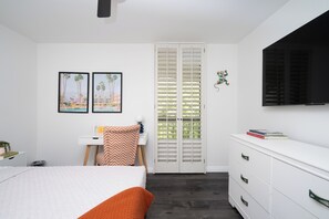 A bedroom with a bed, a dresser, a desk, a chair, a TV, and a closet with a sliding door. - Palm Canyon Retreat, 2bd 2ba with Pool and Patio (Palm Springs)