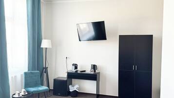 A hotel room with a bed, a desk with a chair, a TV, and a wardrobe.
