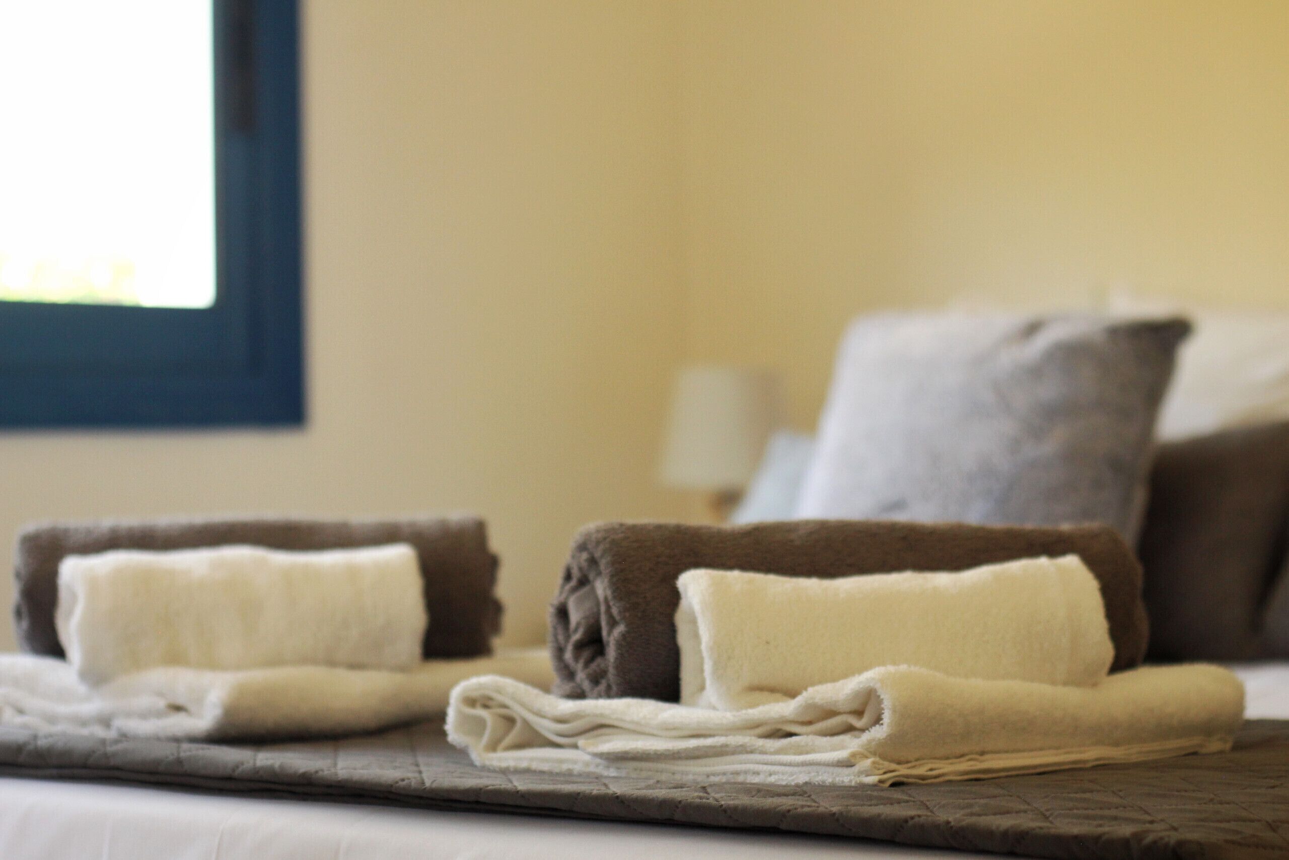 A neatly made bed with folded towels and pillows.