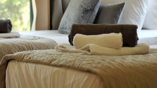 Ein Hotelzimmer mit zwei Betten, beiger Bettwäsche und einem Fenster mit Vorhängen.