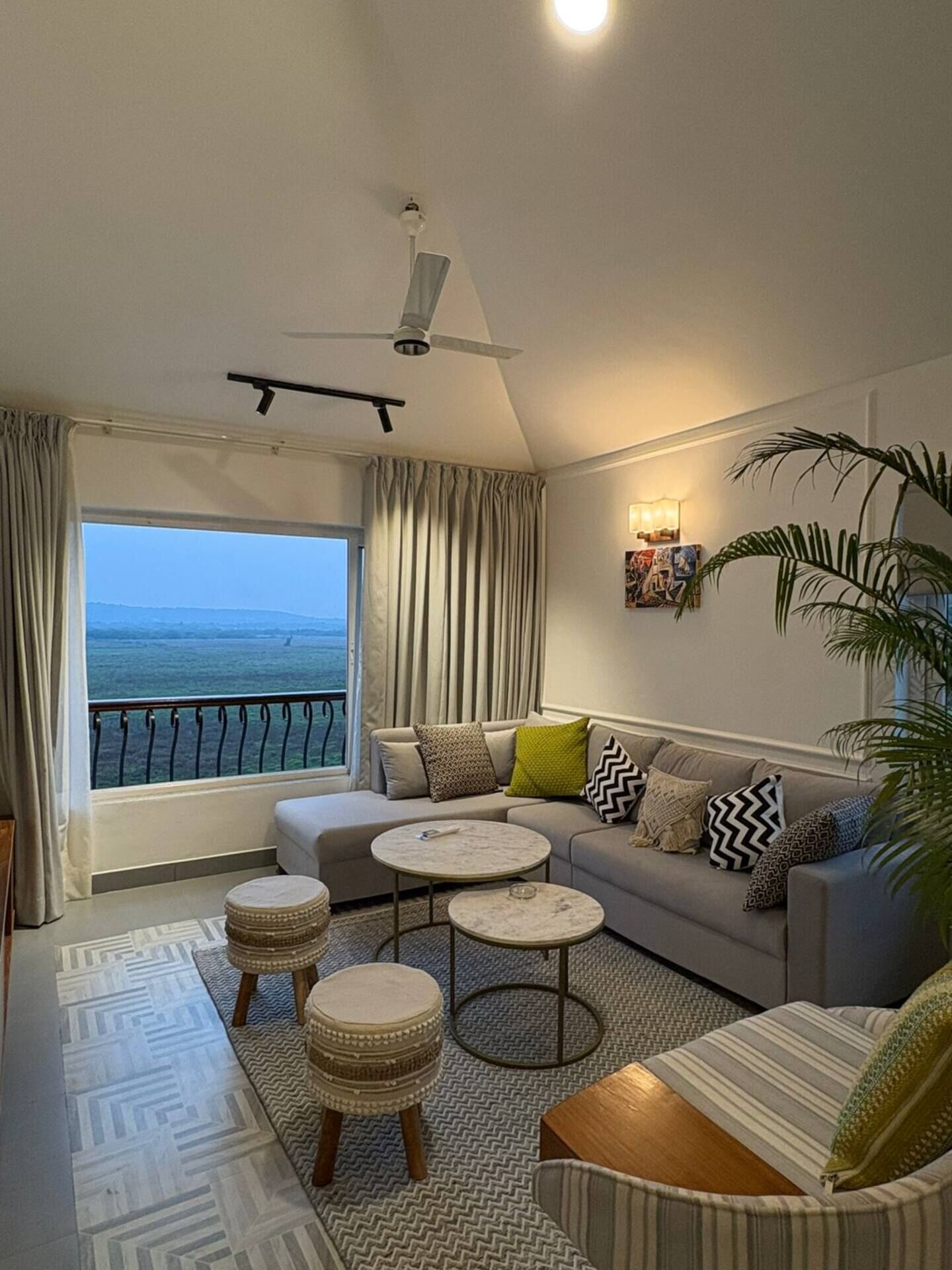 Un salon moderne avec un canapé, deux tables rondes et une vue sur la mer.