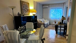 A living room with a glass table, chairs, a sofa, a TV, and a lamp. - Garden view apartment in Sanremo with veranda (Sanremo)