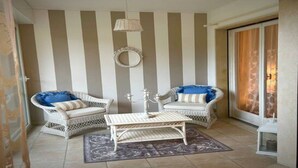 A room with striped walls, wicker furniture, and a patterned rug. - Garden view apartment in Sanremo with veranda (Sanremo)