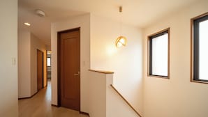 A hallway with wooden flooring, a wooden door, a light fixture, and a window. - ALLURE BEPPU (Beppu)