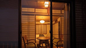 A traditional Japanese room with tatami flooring, a low wooden table, and two chairs. - ALLURE BEPPU (Beppu)