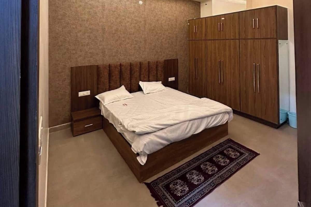 Quarto com cama, guarda-roupa de madeira, ventoinha no teto e iluminação embutida.