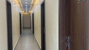 A long, narrow hallway with a wooden door labeled "OFFICE" on the right, leading to a room. - The Divine Cloud Inn (Aligarh)
