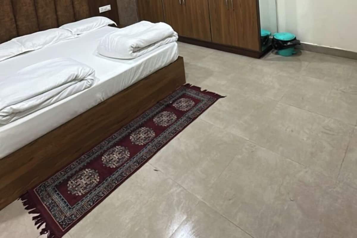 Quarto com cama, guarda-roupa de madeira, ventoinha no teto, ar condicionado e tapete estampado.
