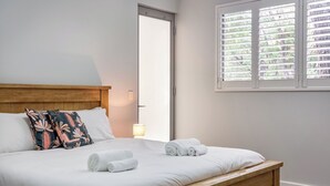 A neatly made bed with white linens, a wooden headboard, and two decorative pillows. - On The Bay: Sundrenched Stunner. Pet-friendly opposite beach. (Quindalup)