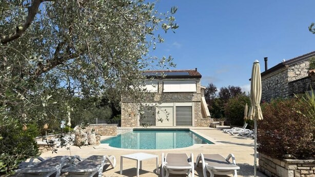 A pool area with lounge chairs, a stone building, and a clear sky. - Relais Borgo San Nicolò (Vilanija)