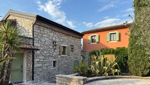 A stone building with a green door and a red building with green shutters. - Relais Borgo San Nicolò (Vilanija)