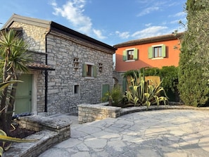 A stone building with a green door and a red building with green shutters.